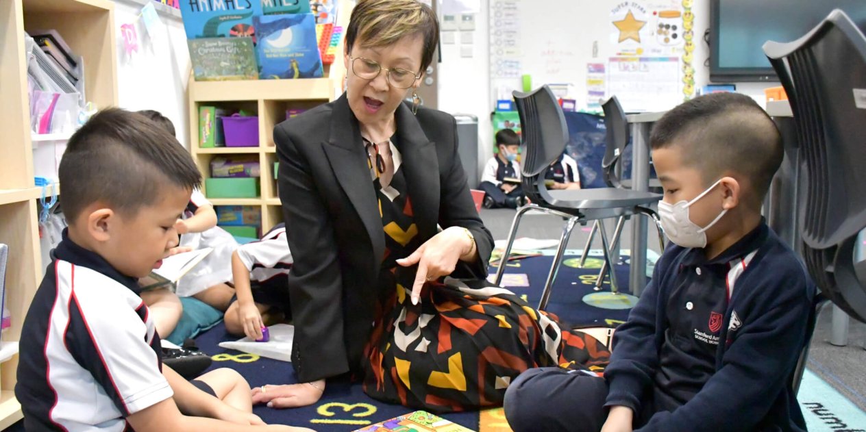 teacher explaining something to two students